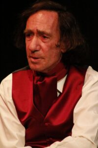 Close-up portrait of Chopin looking away, in a red satin waistcoat and cravat