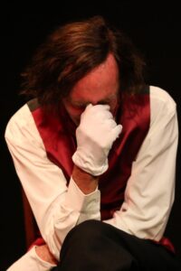 Chopin seated, covering his face with a white-gloved hand