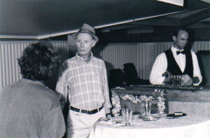 A man in a hat standing at the bar as the barman serves him