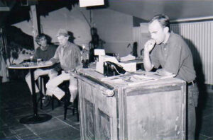 Three men in a country pub, one leaning on the bar counter